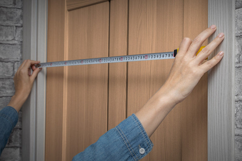 a person using a tape measure to measure width of an internal door